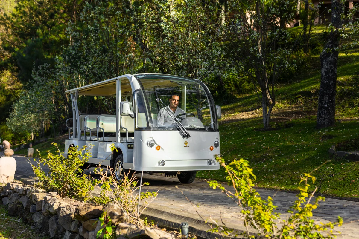 Carrito eléctrico llevando huéspedes por un camino del bosque en el resort