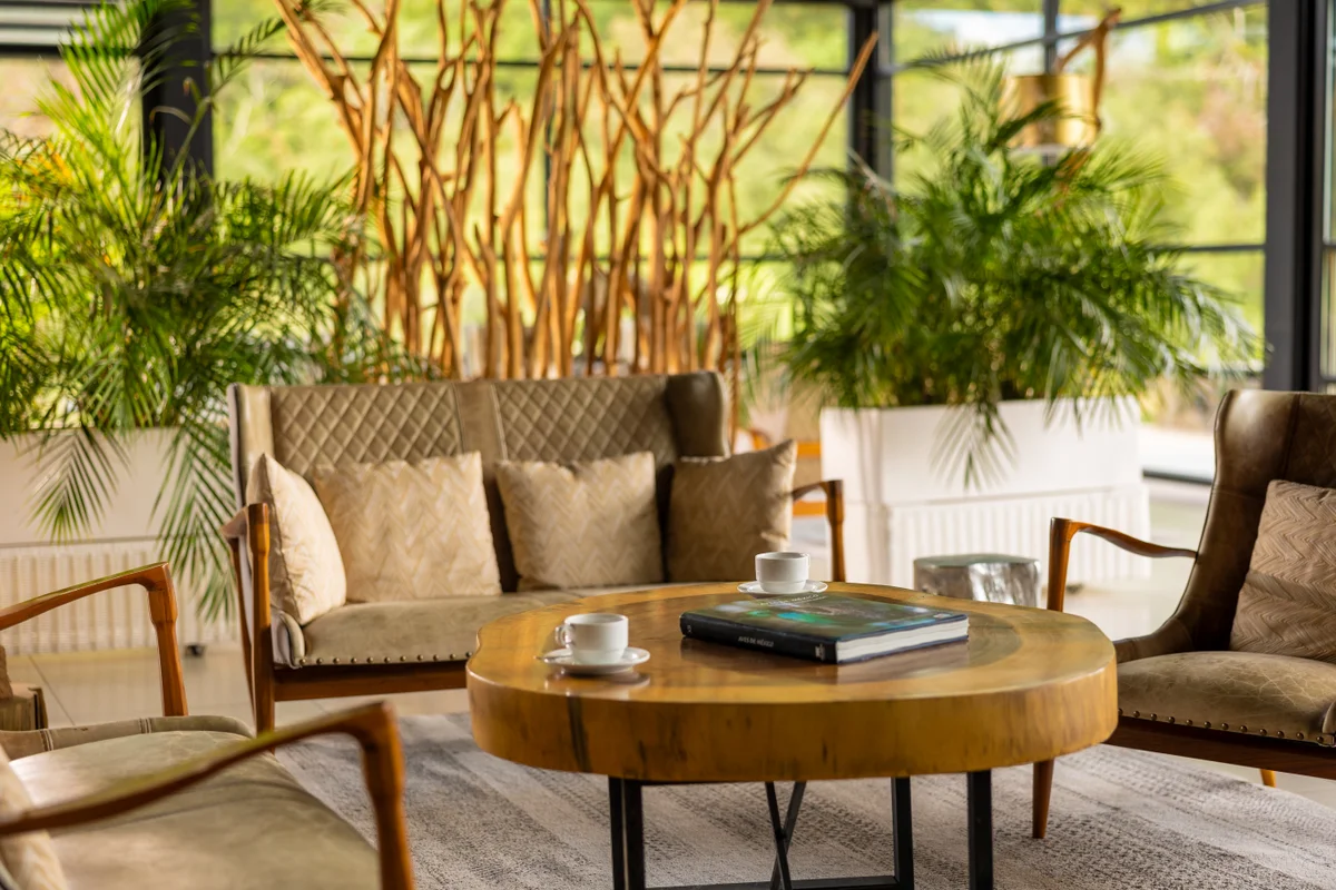 Sofá y sillones alrededor de una mesa de madera rodeados de plantas