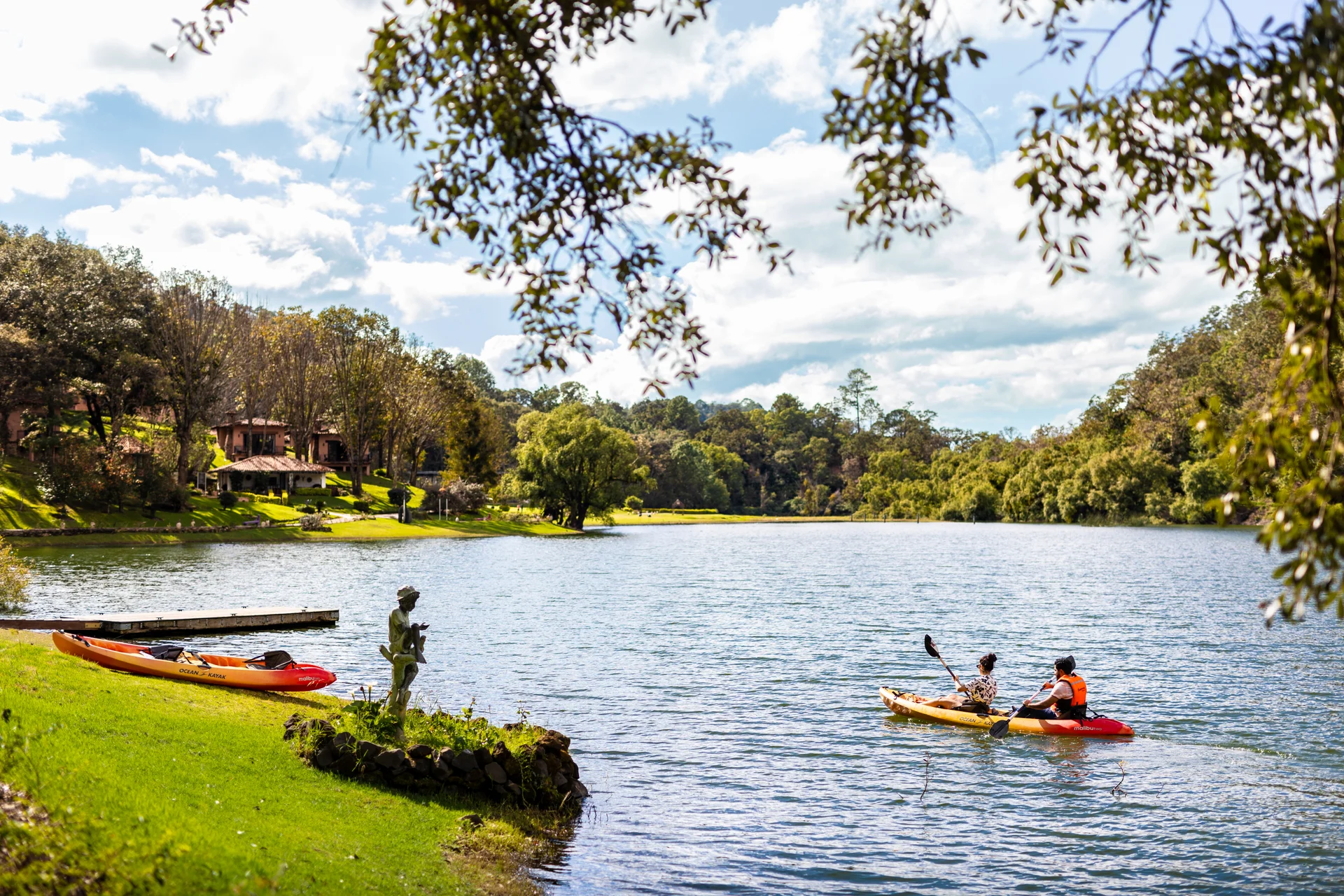 Sierra Lago Resort & Spa - Couple paddling a kayak with the cabins and forest in the background