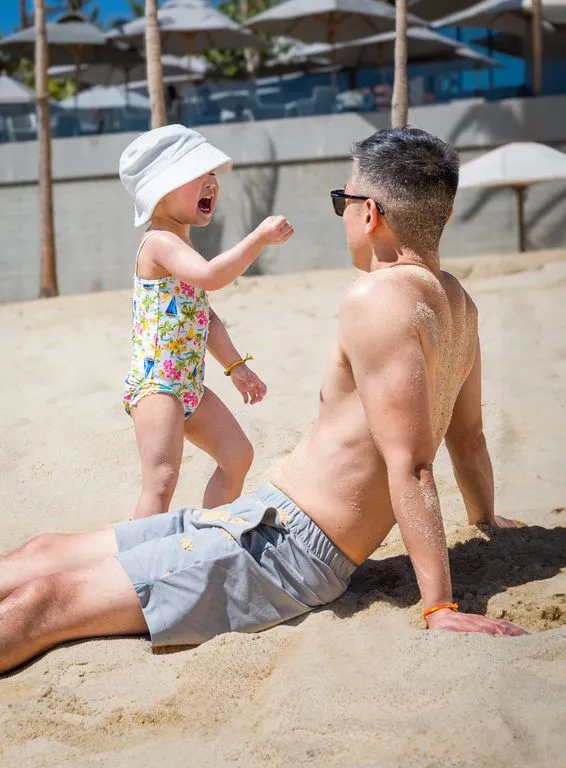kid playing with her dad in the sand