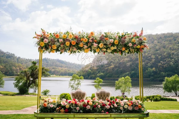 Mesa de novios con arreglo floral y dos sillones frente al lago y el bosque