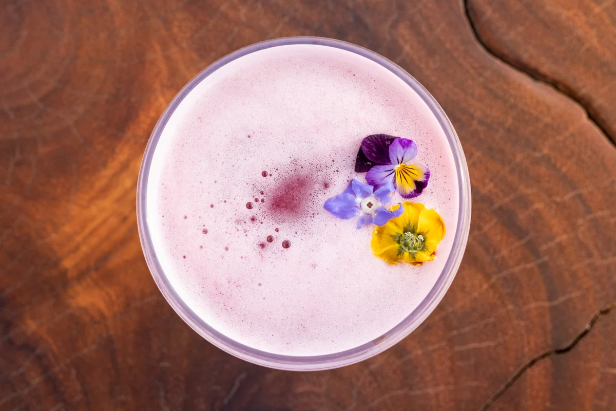 Pink cocktail garnished with edible flowers at Garza Blanca Los Cabos