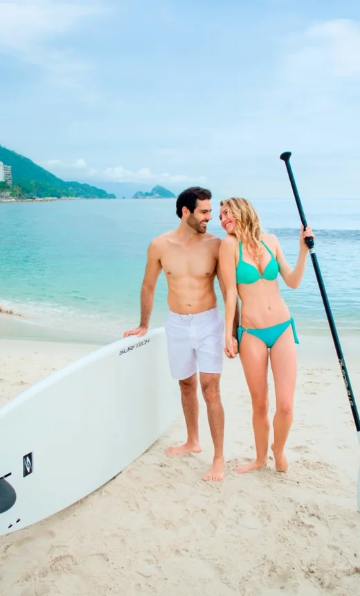 Couple with a paddleboard on the beach at Garza Blanca Puerto Vallarta