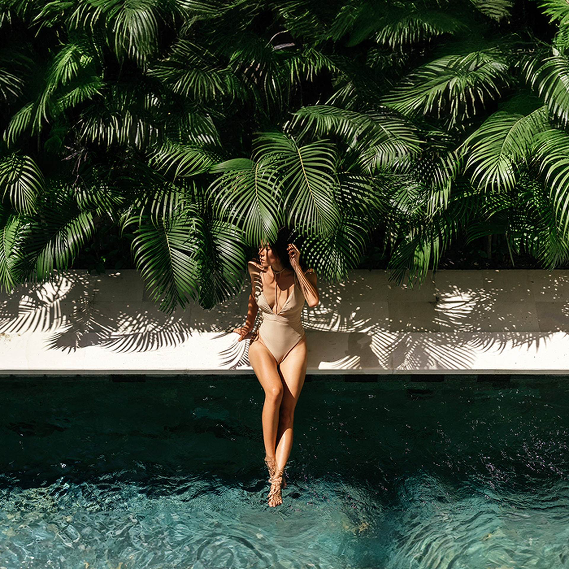 Guest relaxing by a pool surrounded by lush jungle foliage