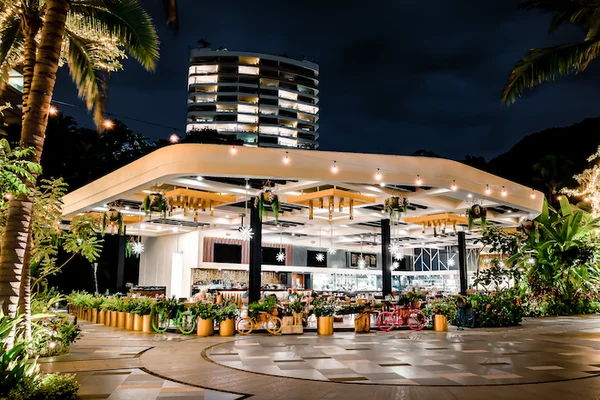 Garza Blanca Puerto Vallarta open-air beachfront restaurant by night, illuminated palms, lush plants and colorful bikes; Escape to the Extraordinary.