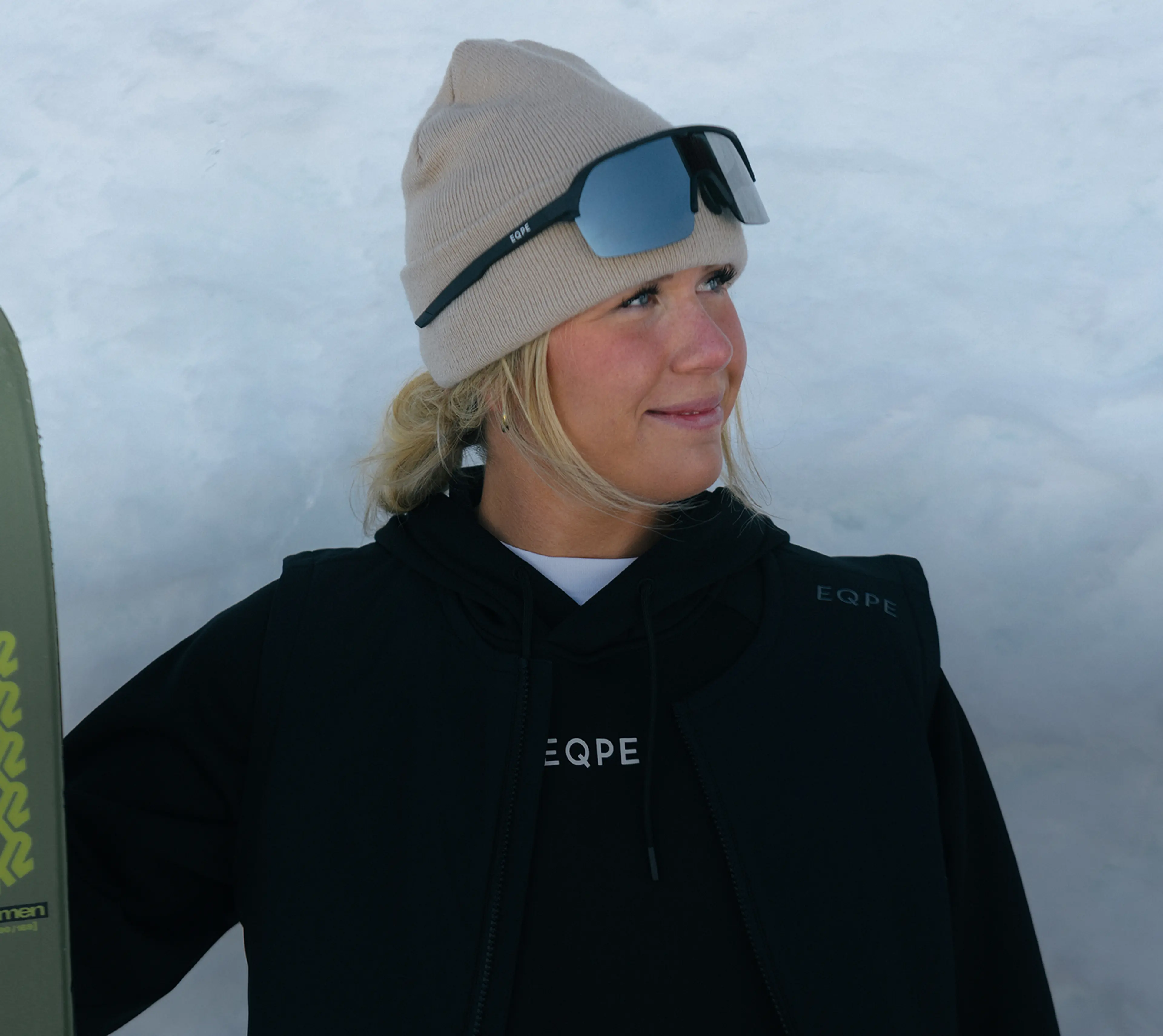 Julia Larsson with a beanie and sunglasses, standing against a snowy backdrop