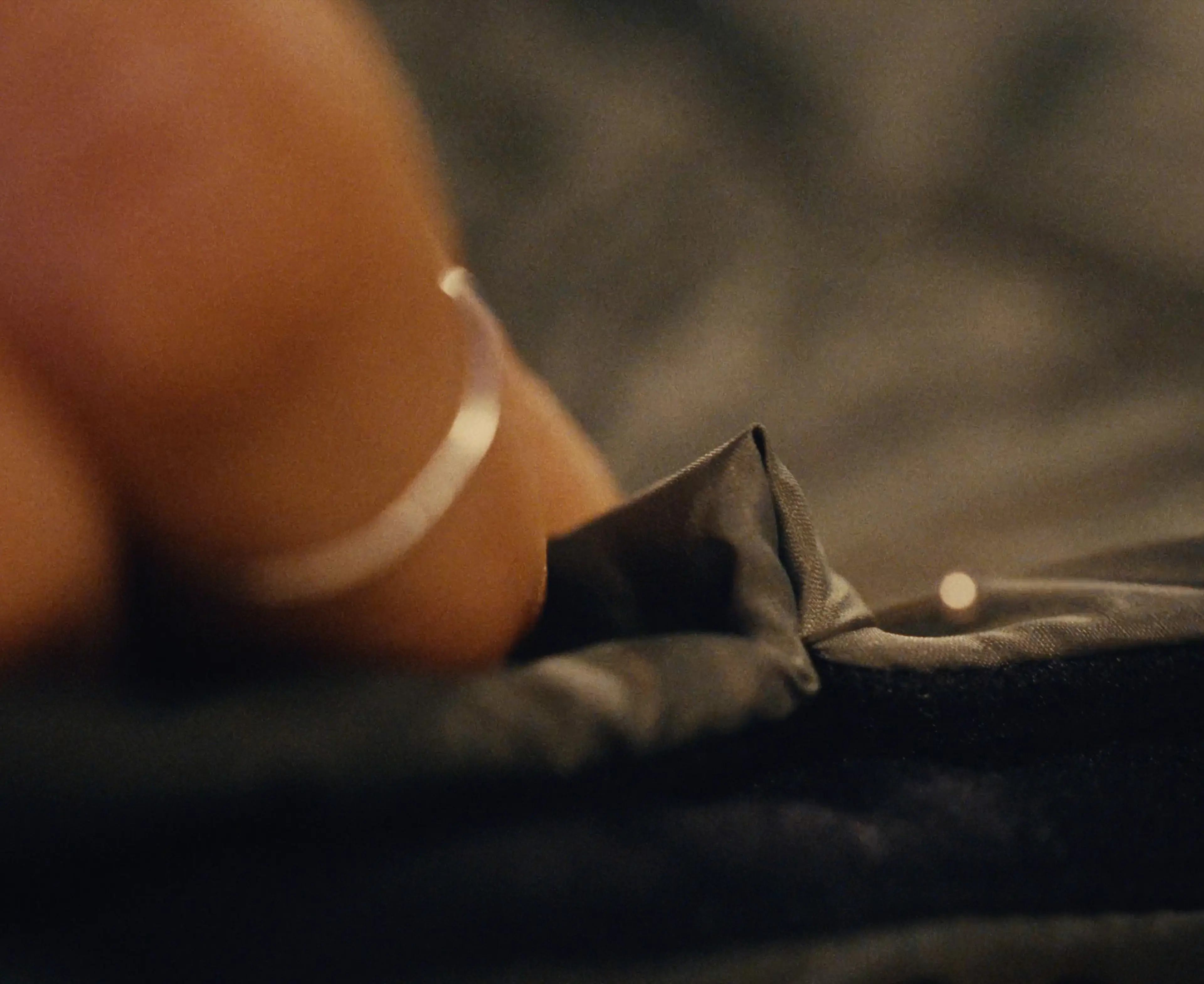 A close-up of Sara's hand, holding a piece of dark fabric