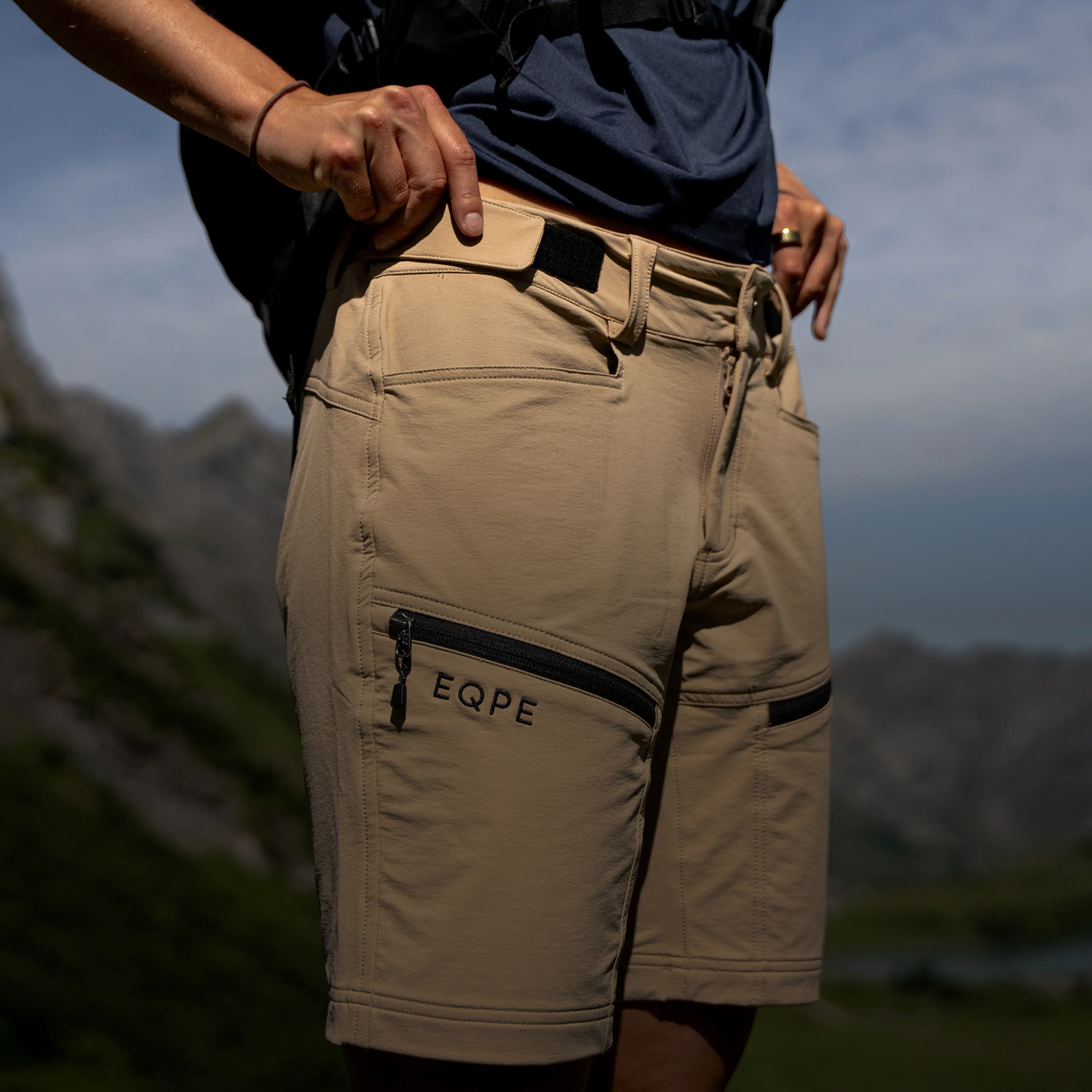 Person in tan hiking shorts with zippered pocket.