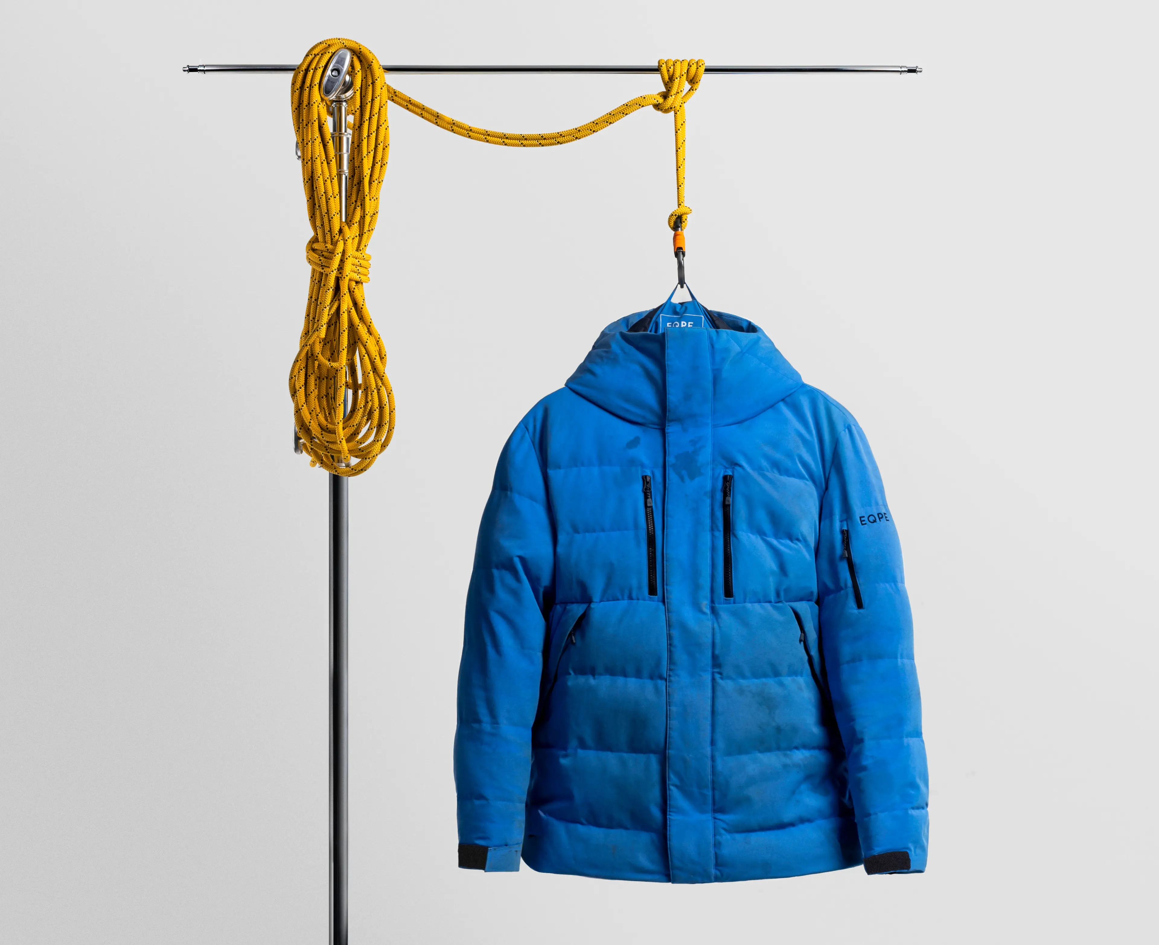 Blue worn and torn puffer jacket displayed on a stand