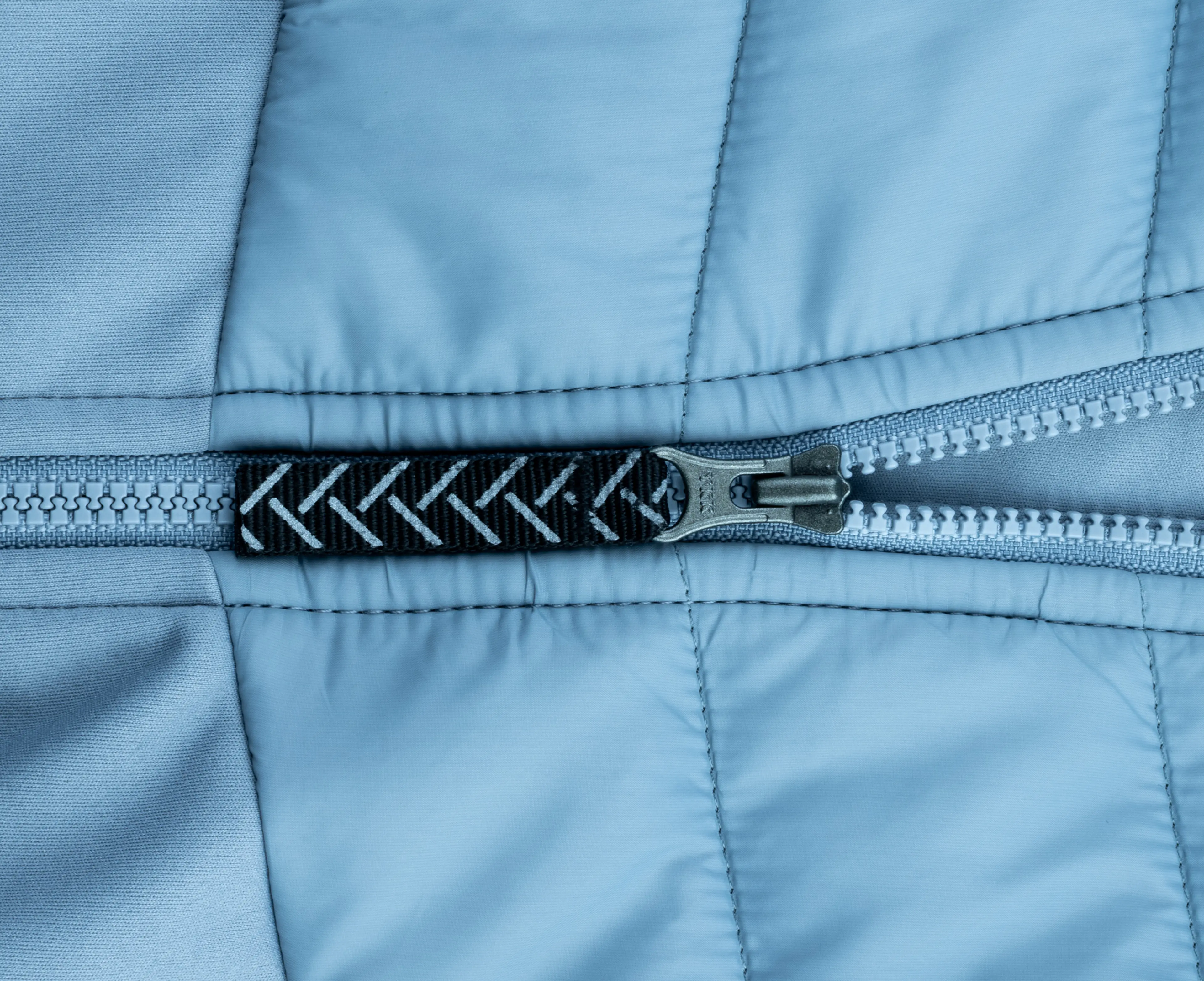 Close-up of a metallic zipper on light blue quilted fabric