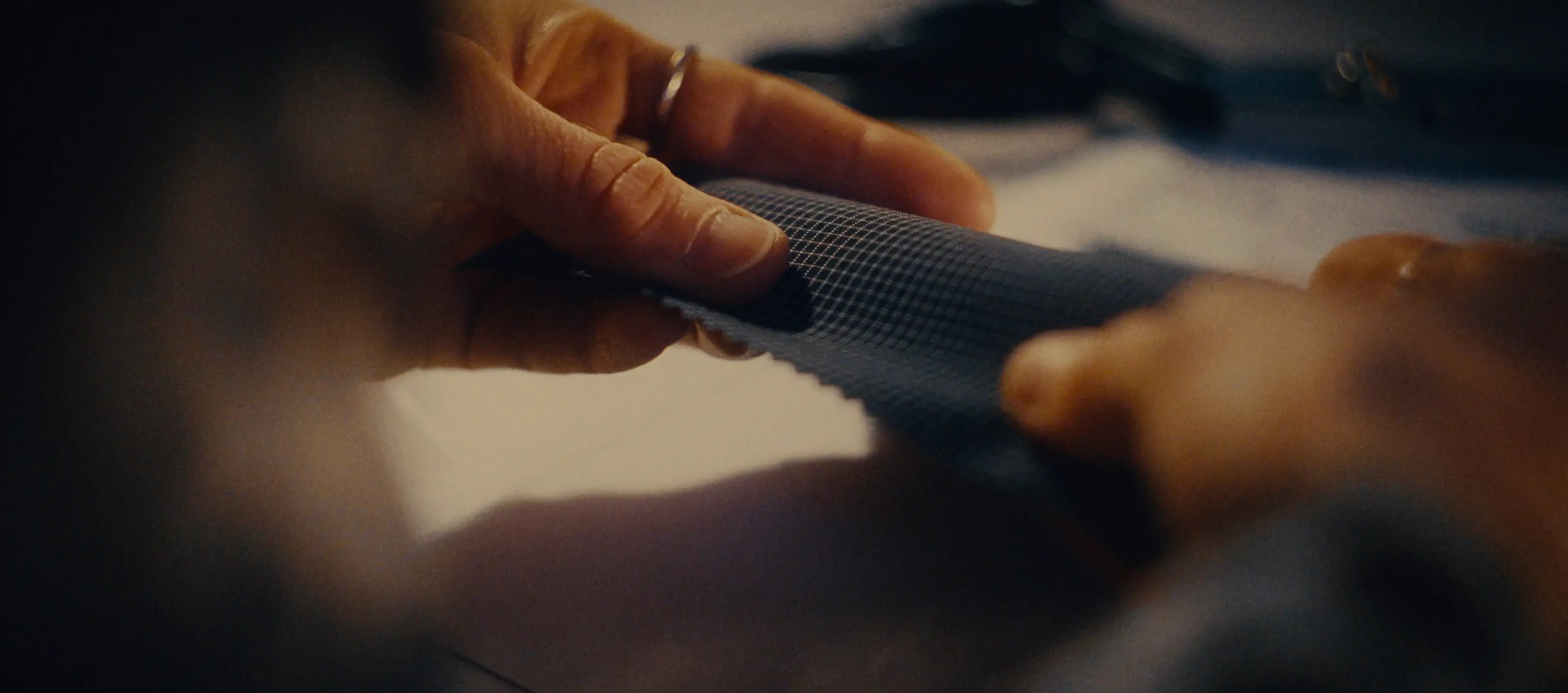 Sara's hands holding and examining a piece of textured grey fabric with careful attention
