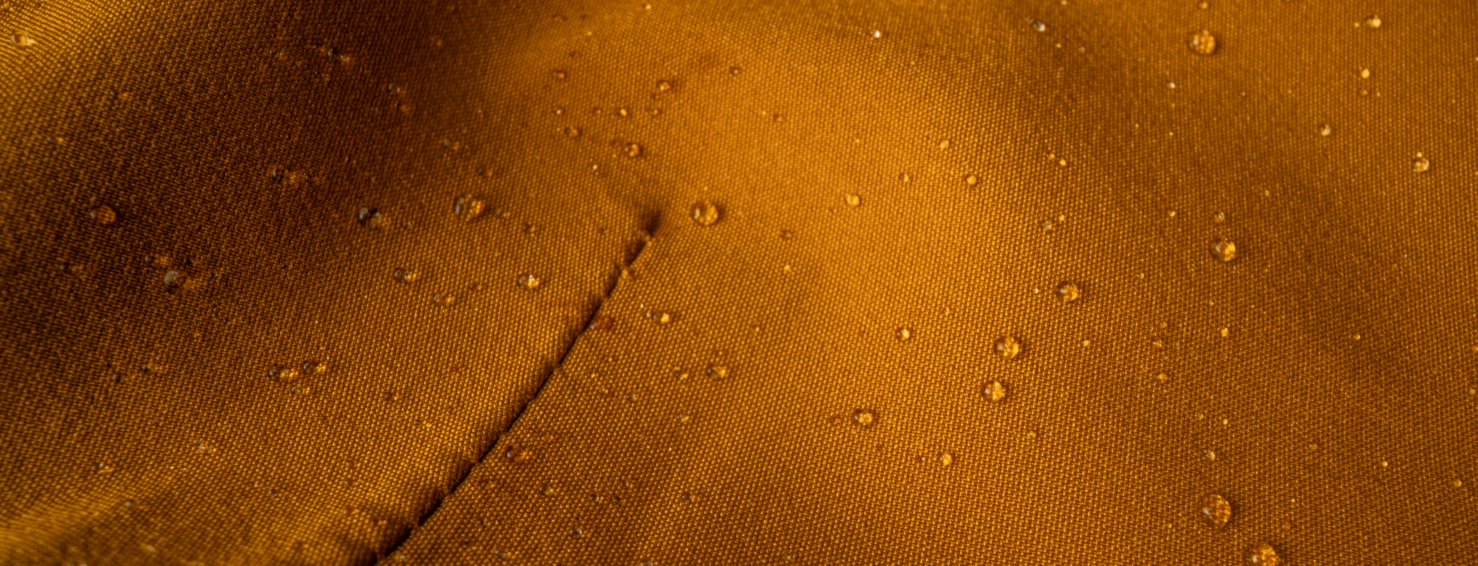Close up picture of water repellent yellow fabric with water drops on it