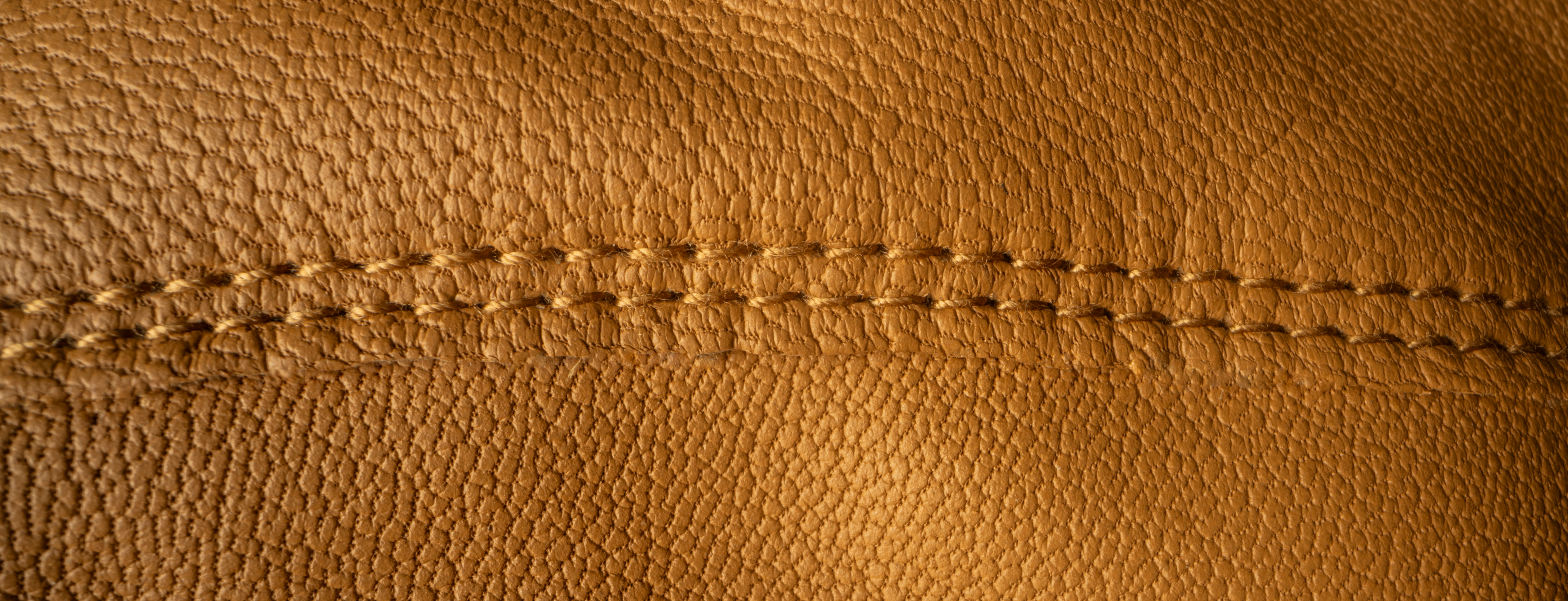 Close up picture of yellow leather with stitches