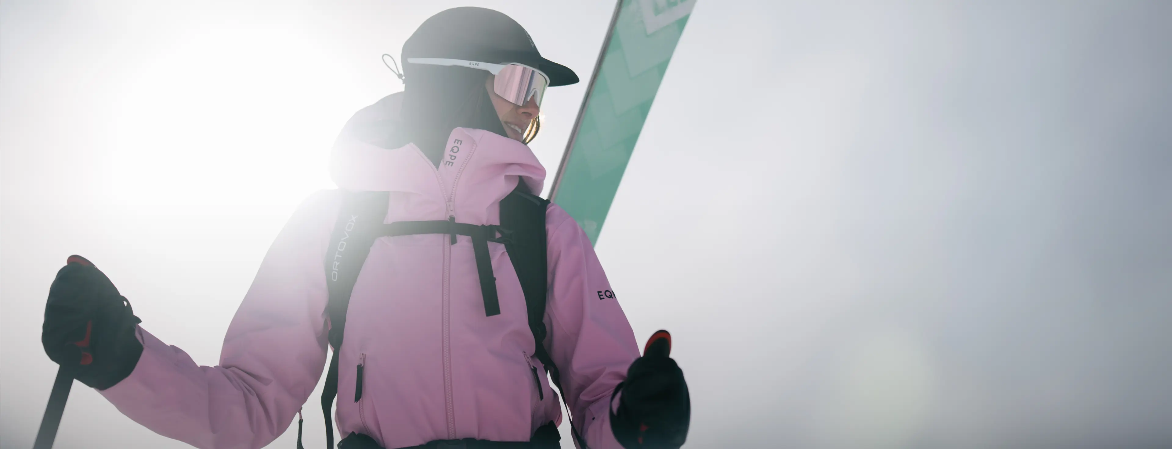 Person in a pink jacket and helmet, holding ski poles.