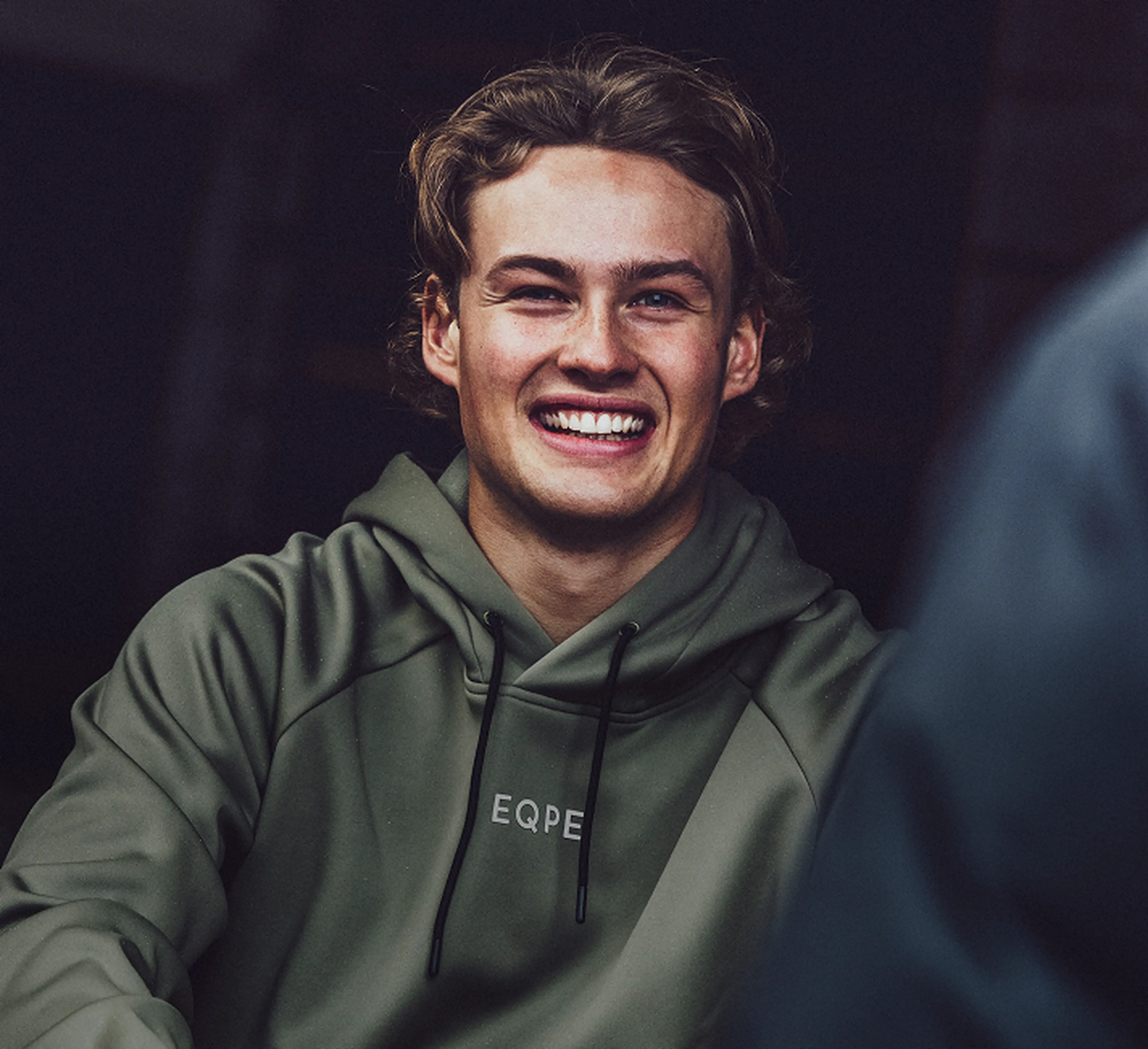 Erik Jonsson in a green hooded sweatshirt, sitting against a dark background.