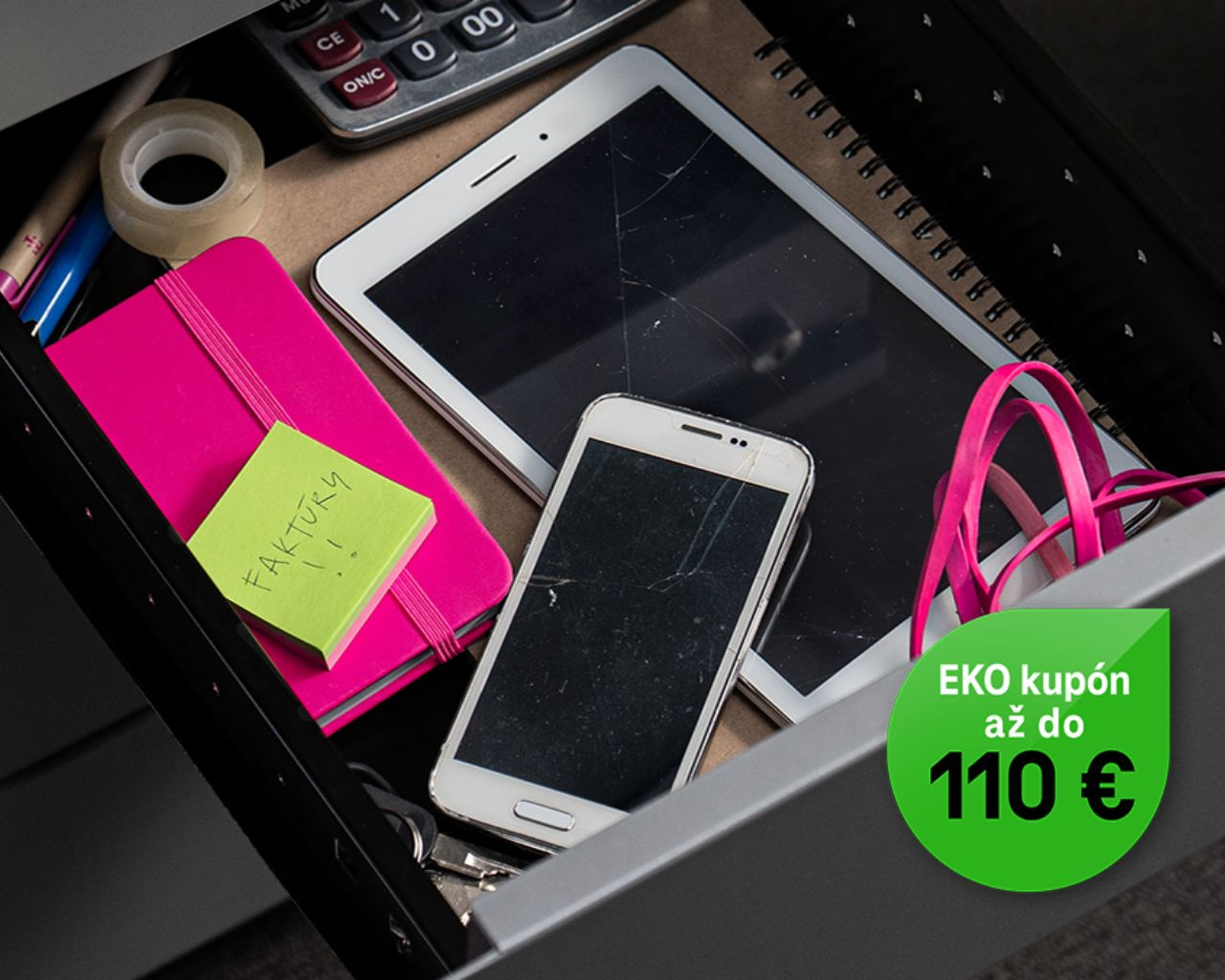 Otvorená zásuvka s prasknutým tabletom, smartfónom, ružovým zápisníkom, lepiacim papierikom, páskou, kalkulačkou a zelenou propagačnou nálepkou so zľavou.