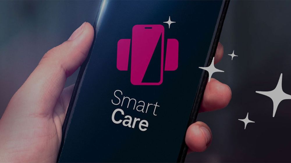Ruka držiaca smartfón zobrazujúci logo s ružovou ikonou telefónu a textom „Smart Care“ na obrazovke.