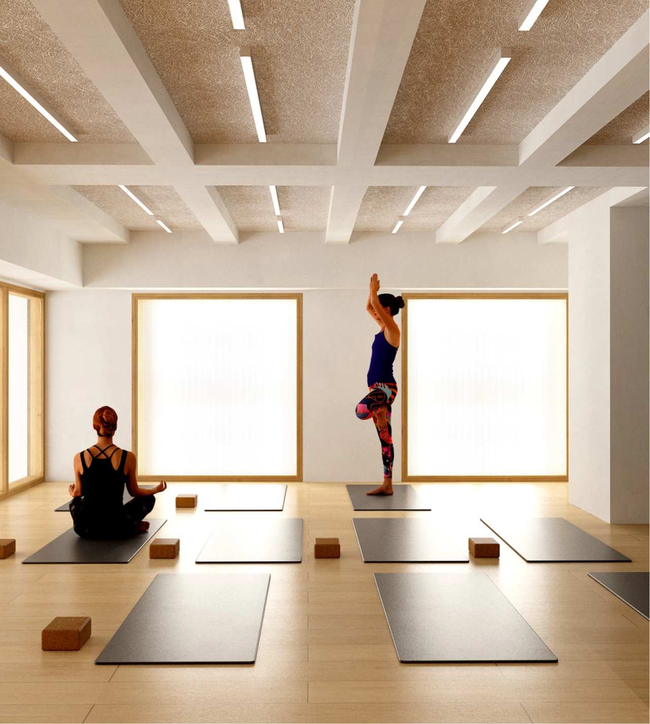 Caudalie Studio Two people in a brightly lit yoga studio, one sitting cross-legged, the other standing in a tree pose, surrounded by yoga mats and blocks.