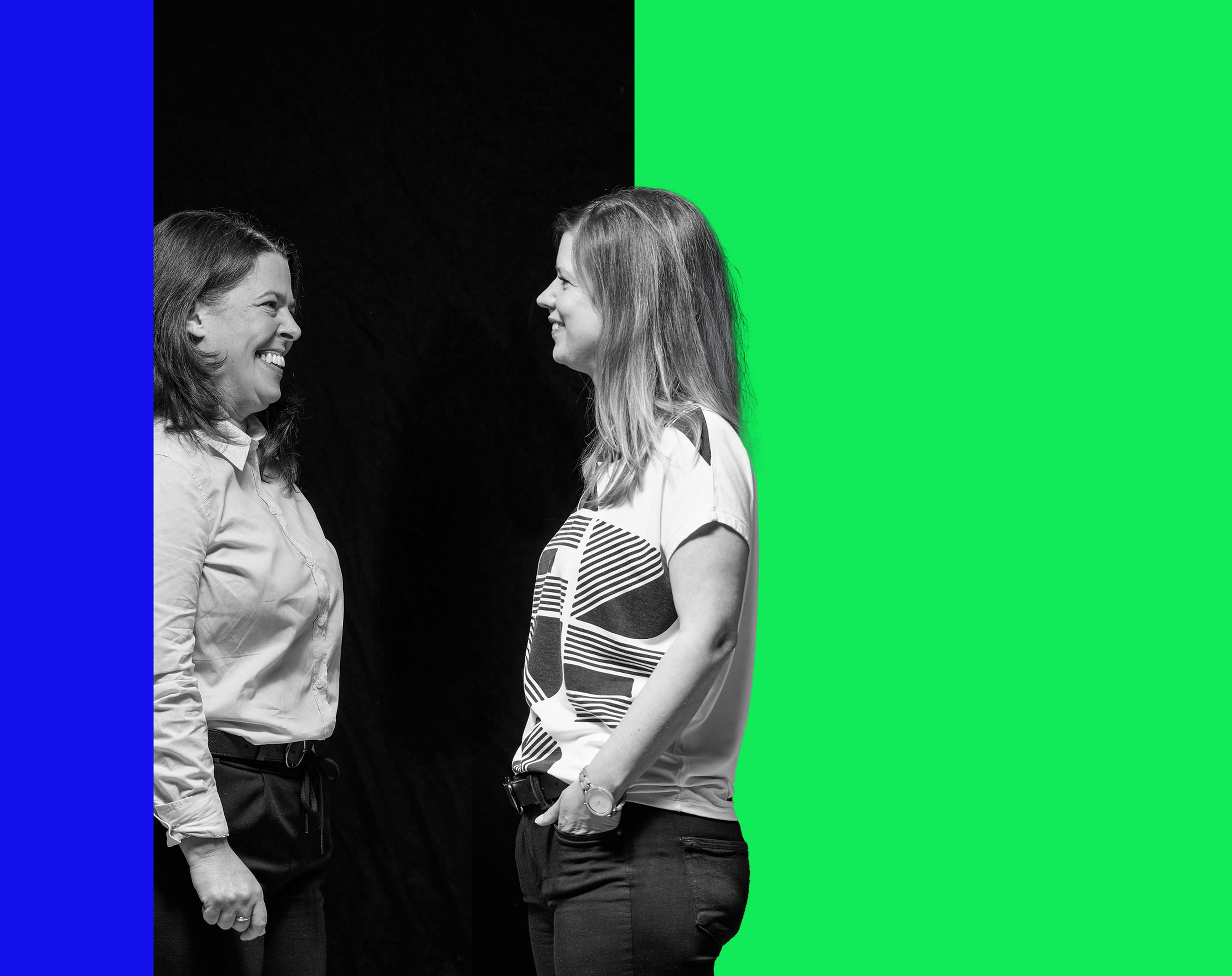 Gabriele und Valeria Ölz stehen sich gegenüber, lächeln und unterhalten sich, vor einem dunklen Hintergrund.