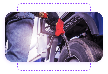Person refueling a truck with a red fuel nozzle at a gas station, with a focus on the vehicle's wheel.