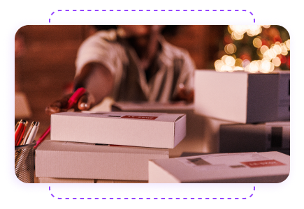 A person reaching for a stack of gift boxes with a festive background.