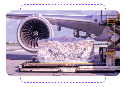 Airplane cargo wrapped in plastic on a pallet near a jet engine on the tarmac.