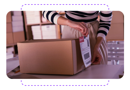 Person in striped shirt and skirt applying a shipping label to a cardboard box in a storage room with shelves.