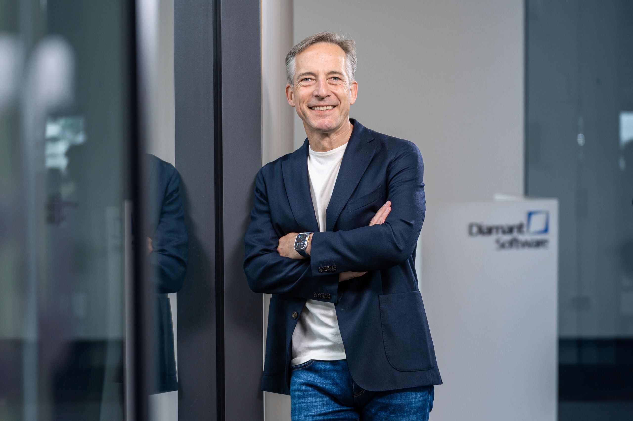 Sven Krüger lehnt lächelnd an einer Wand. Im Hintergrund das Logo Diamant Software.