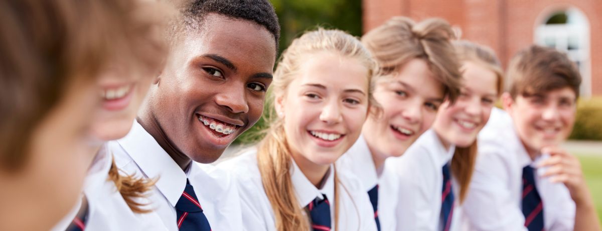 Smiling students in uniforms sitting outdoors, representing private schools served by BMWL’s accounting and assurance services.