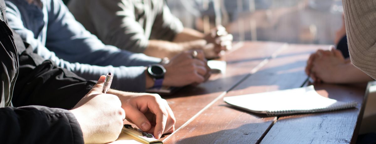 Business professionals meeting at a wooden table, discussing organizations served by our nonprofit accounting firm.