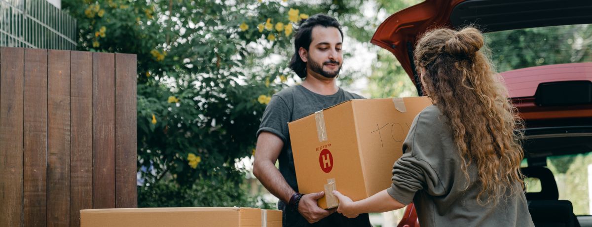 Two people unloading cardboard boxes of donations from a car trunk in an outdoor setting, illustrating activities commonly associated with charitable organizations served by BMWL’s accounting and assurance services.