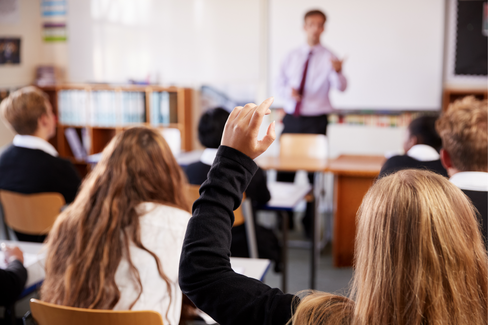 Students in uniforms inside a classroom, with one student raising their hand, representing private schools served by BMWL’s accounting and assurance services.