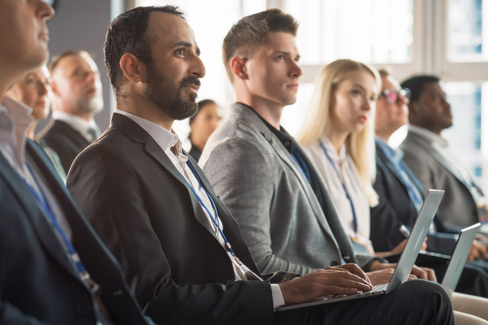 Diverse group of professionals seated and looking forward during a presentation, some with laptops, representing nonprofit associations supported by BMWL’s accounting and assurance services.