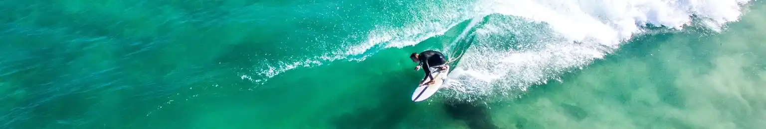 The image depicts an exhilarating scene of a person surfing on a green ocean wave.