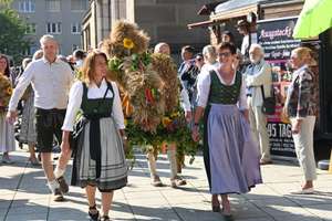 Eine Erntekrone wird in Richtung Kirche getragen.