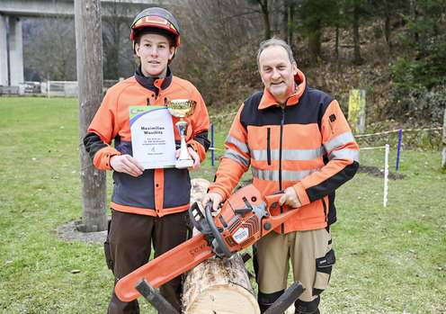 Schüler und Lehrer mit Motorsäge, Pokal und Urkunde