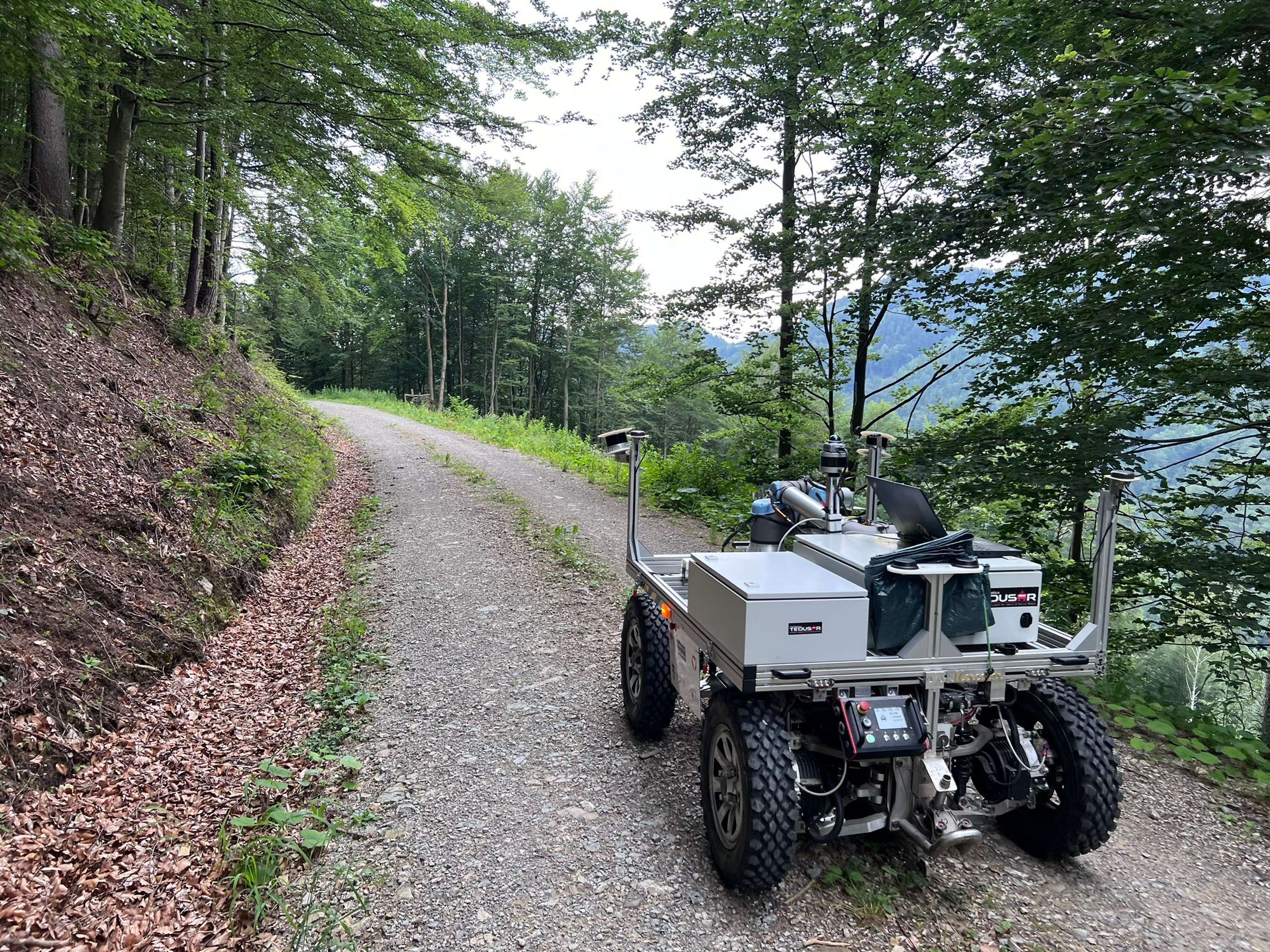 Ein autonom fahrender Roboter auf einem Forstweg.