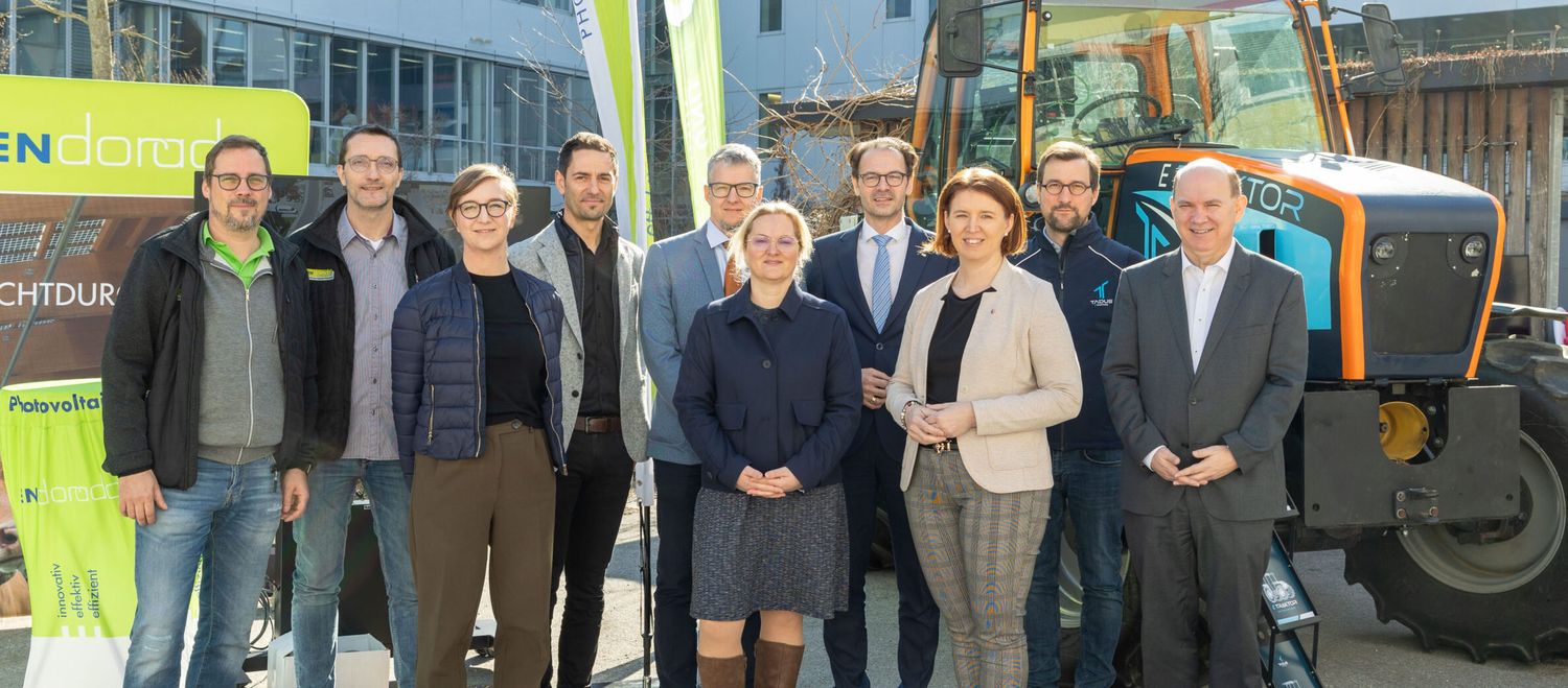 Die Projektbeteiligten mit dem batterieelektrischen Traktor, der als mobiler Energiespeicher am Hof dienen soll.