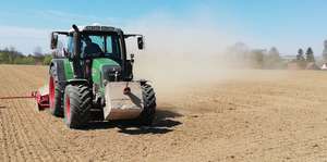 Traktor auf dem Feld wirbelt Staub auf.