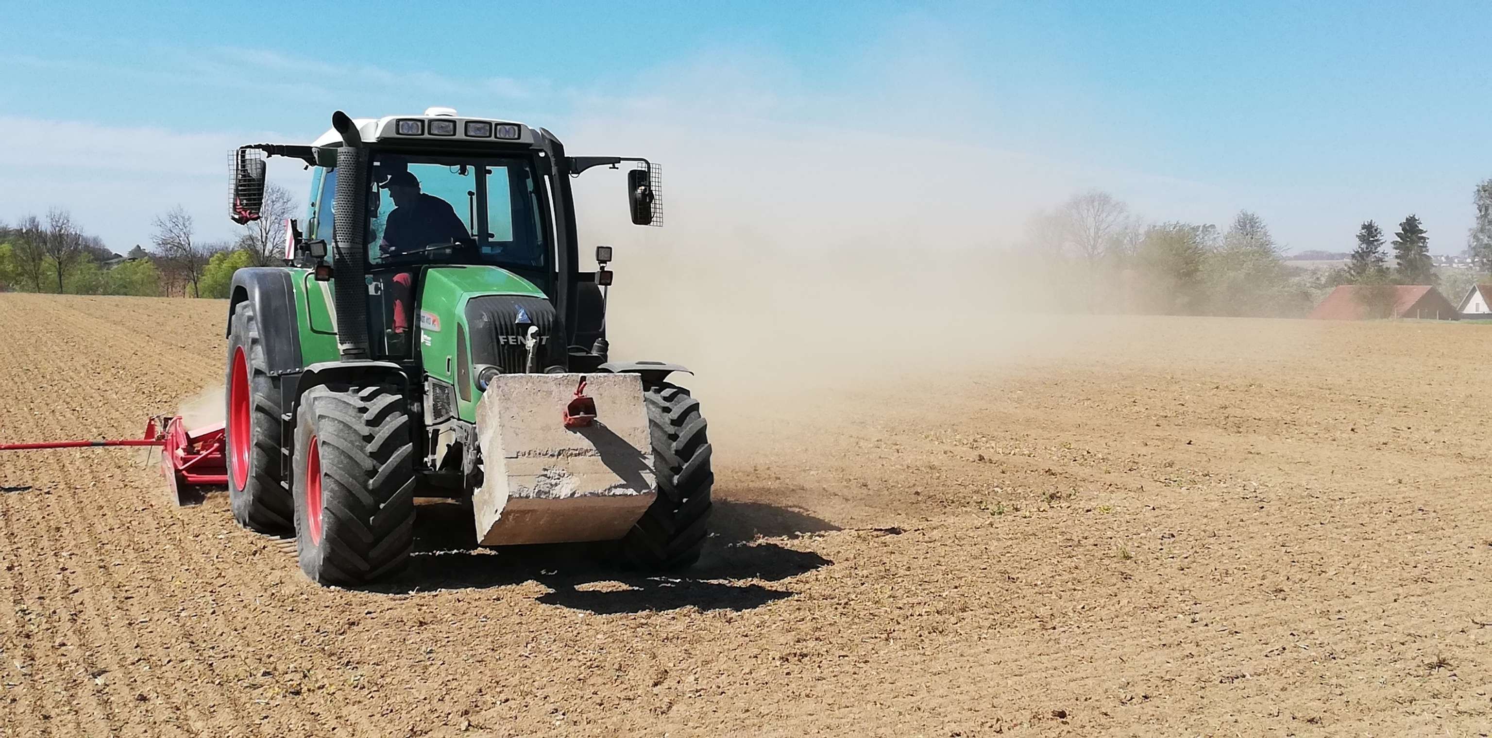Traktor auf dem Feld wirbelt Staub auf.