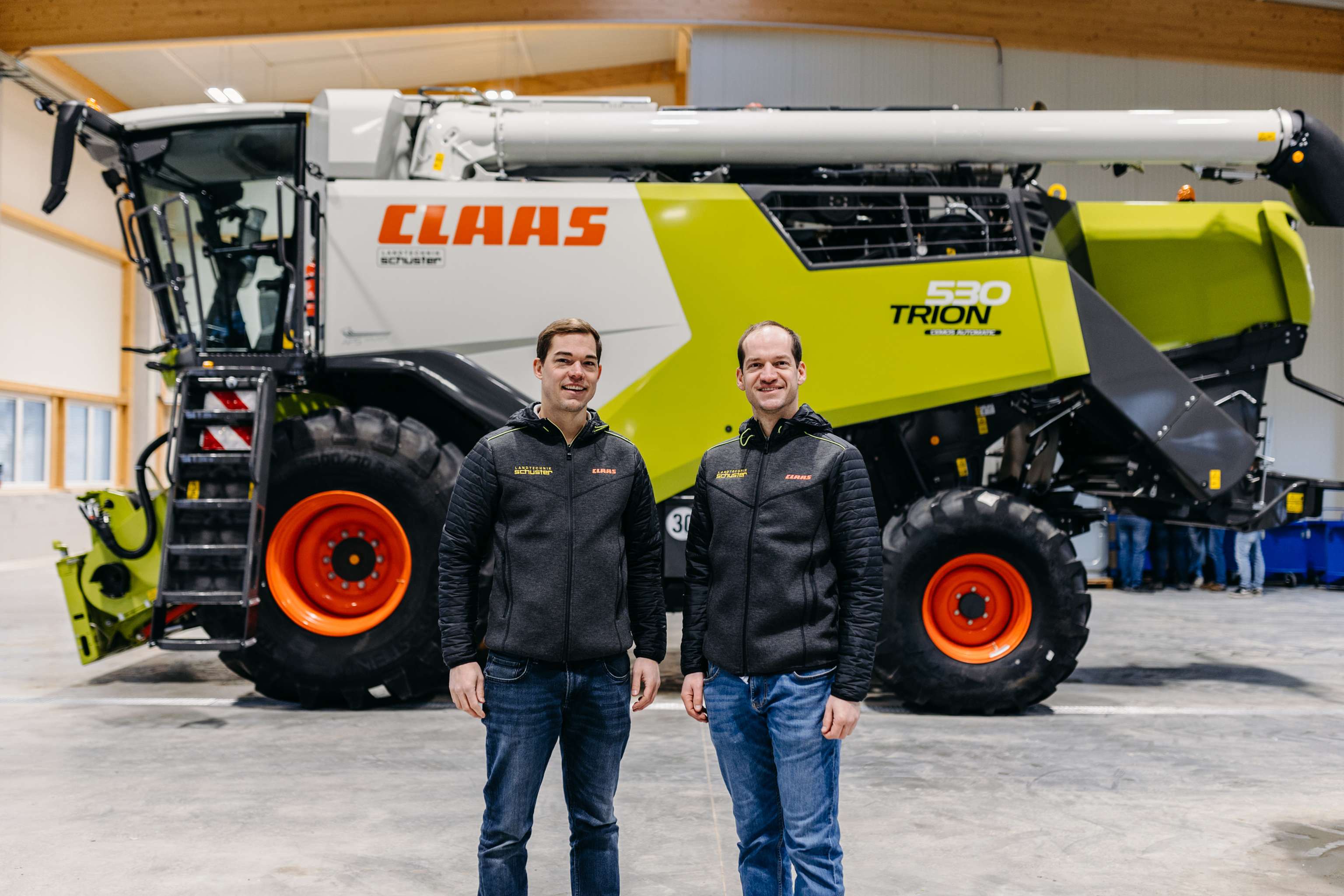 Zwei Personen vor einem Claas-Traktor stehend