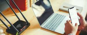 Closeup Of A Wireless Router And A Man Using Smartphone On Living Room At Home Ofiice , Concepts Wifi Connect .