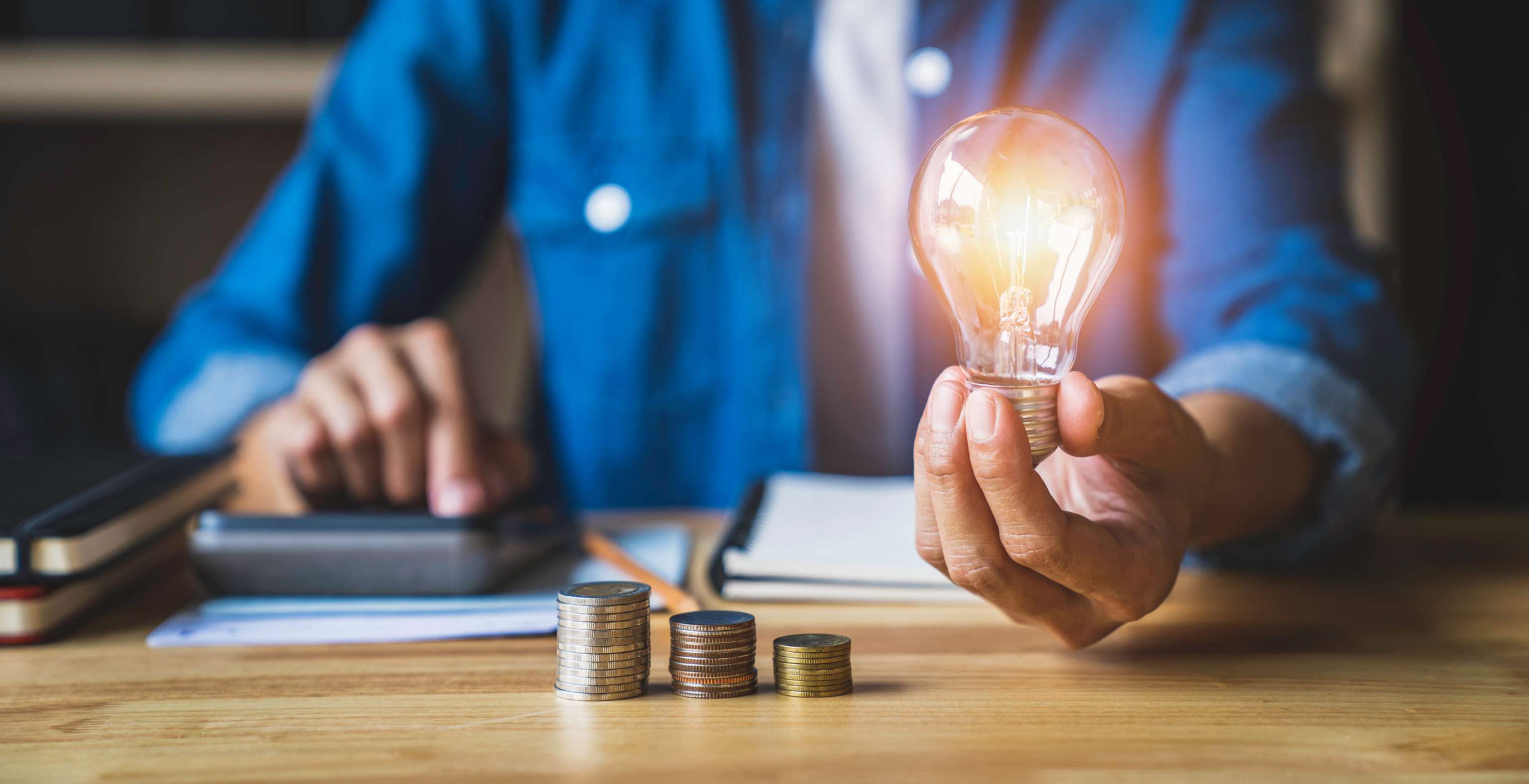 Business Woman Hand Holding Lightbulb With Using A Calculator To