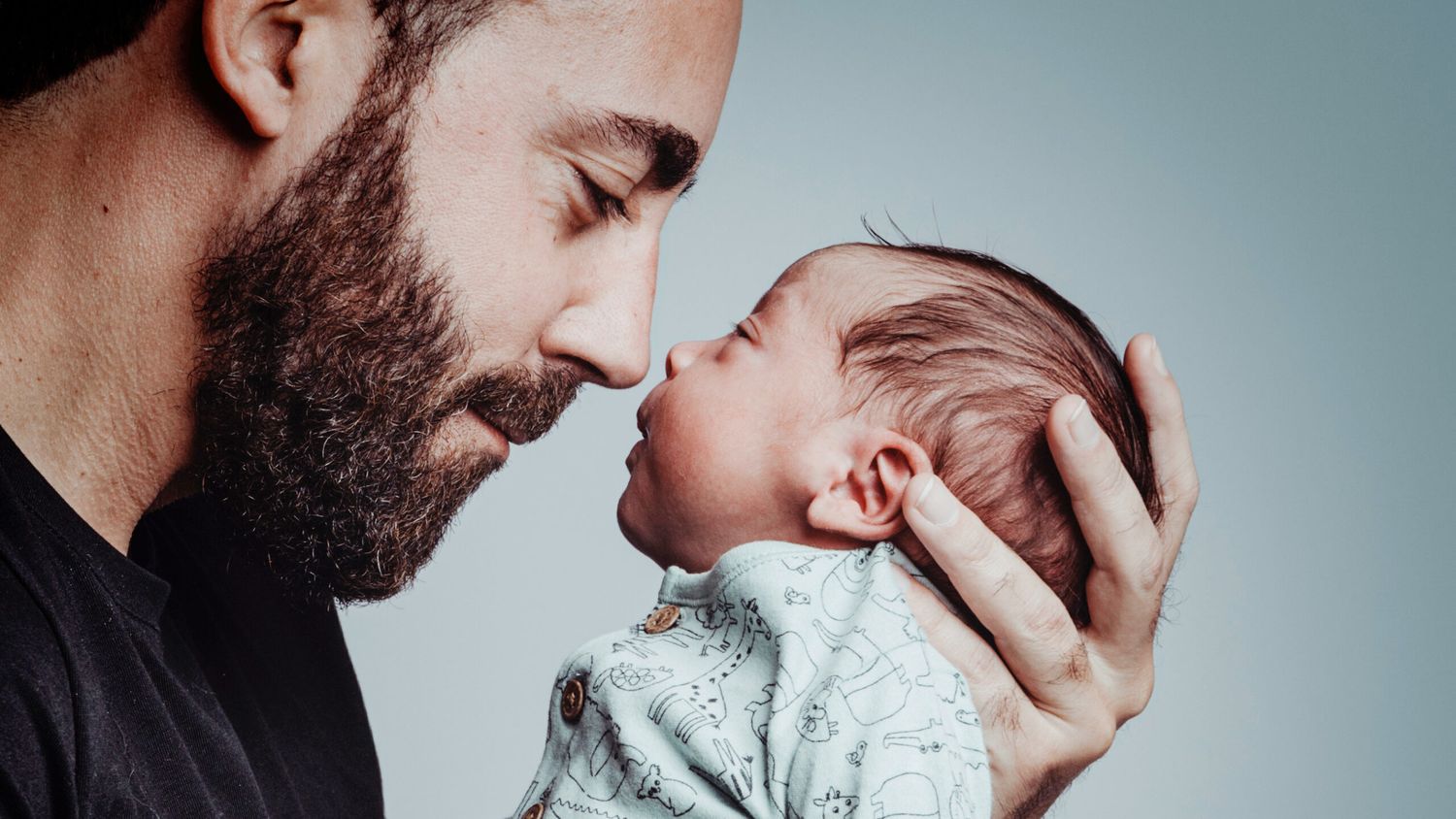 Portrait Of Man Looking At His Newborn Son With Loving Expression