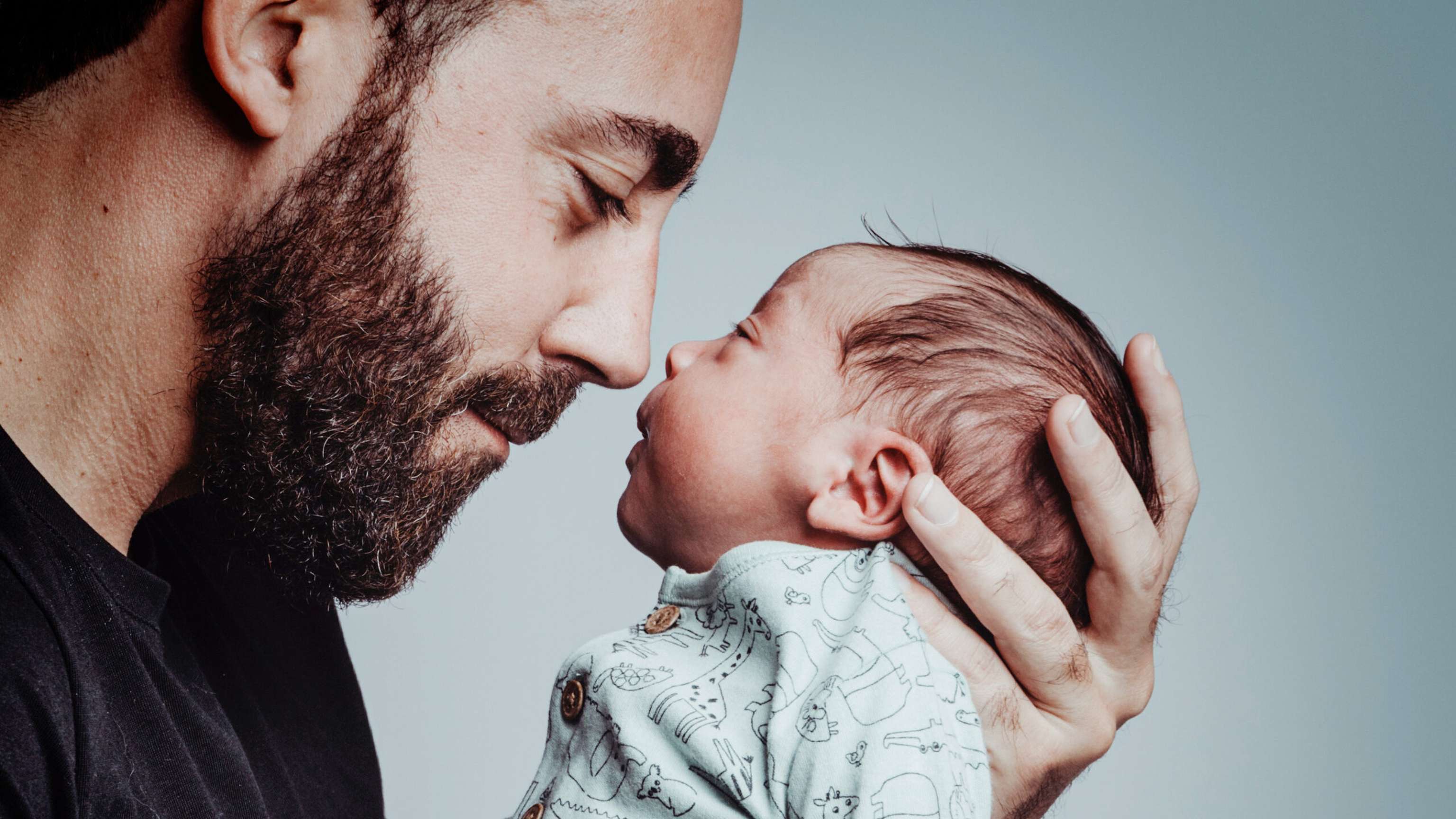 Portrait Of Man Looking At His Newborn Son With Loving Expression