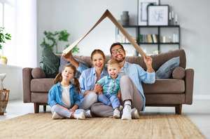 Concept Of Housing And Relocation. Happy Family Mother Father And Kids With Roof At Home