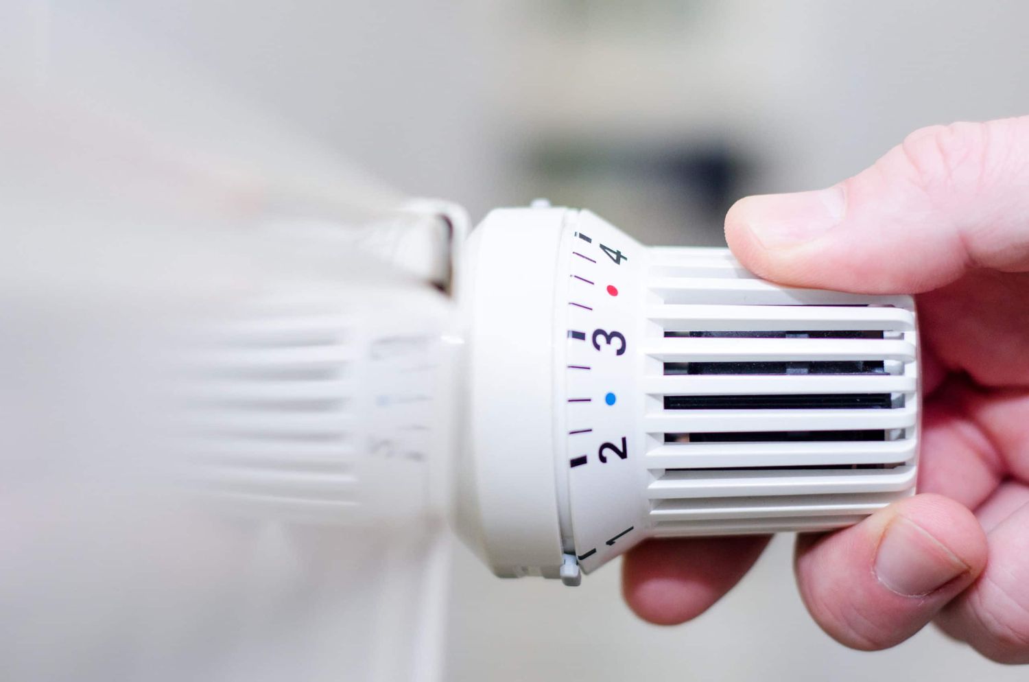 Close Up Of Hand Adjusting Heating Thermostat.