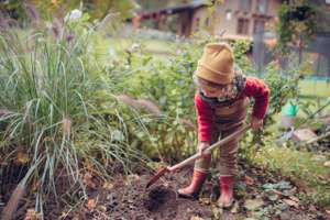 Litlle Girl Taking Care Of Vegetable Garden, Spading Soil.