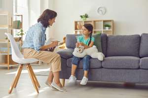 Female Child Psychologist Working With A Little Preschool Girl In A Bright Office.