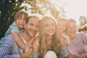 Dream Summer Weekend Countryside Backyard Relax Concept. Mom Dad And Their Little Kids Girls Boys Hug Embrace Enjoy Sunset Evening Park Garden Day Outdoors